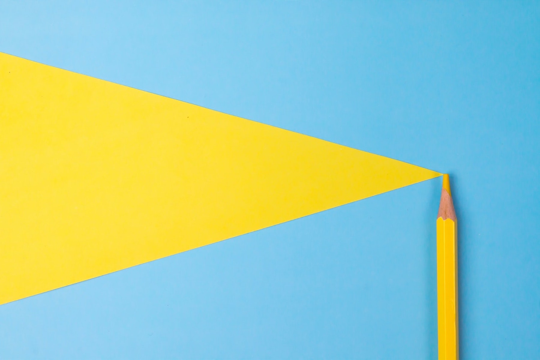 Yellow pencil creating a bold yellow shape on a blue background